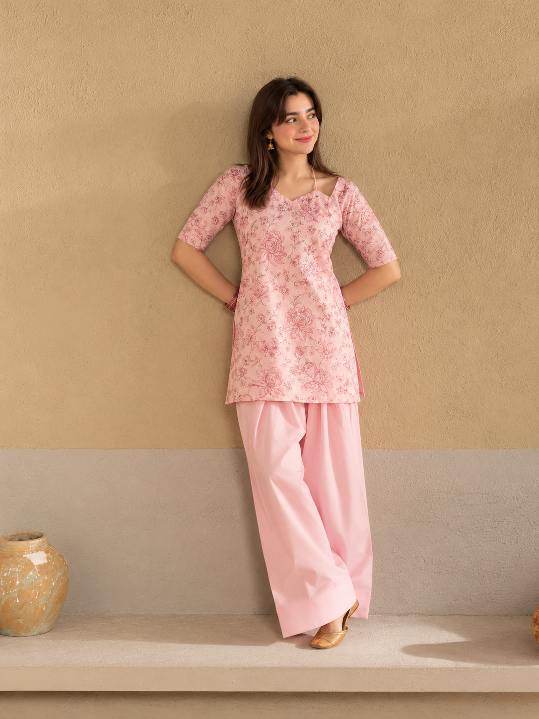 Bahaar Bloom pink floral crepe shirt with plain wide-leg trousers, wall pose view.