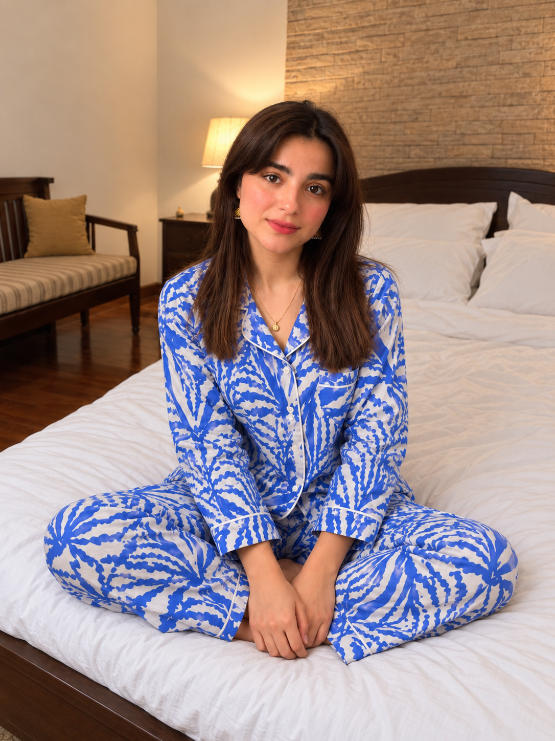 Blue Breeze blue and white linen night suit, seated cross-legged on the bed.