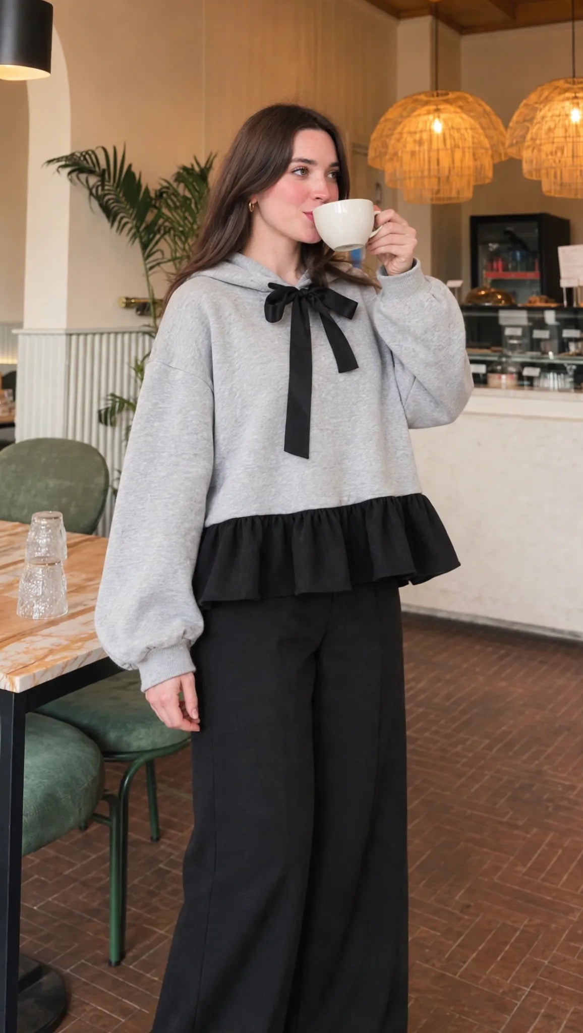 Bow Ruffle Hoodie in grey with black ribbon and ruffle hem, coffee-side view
