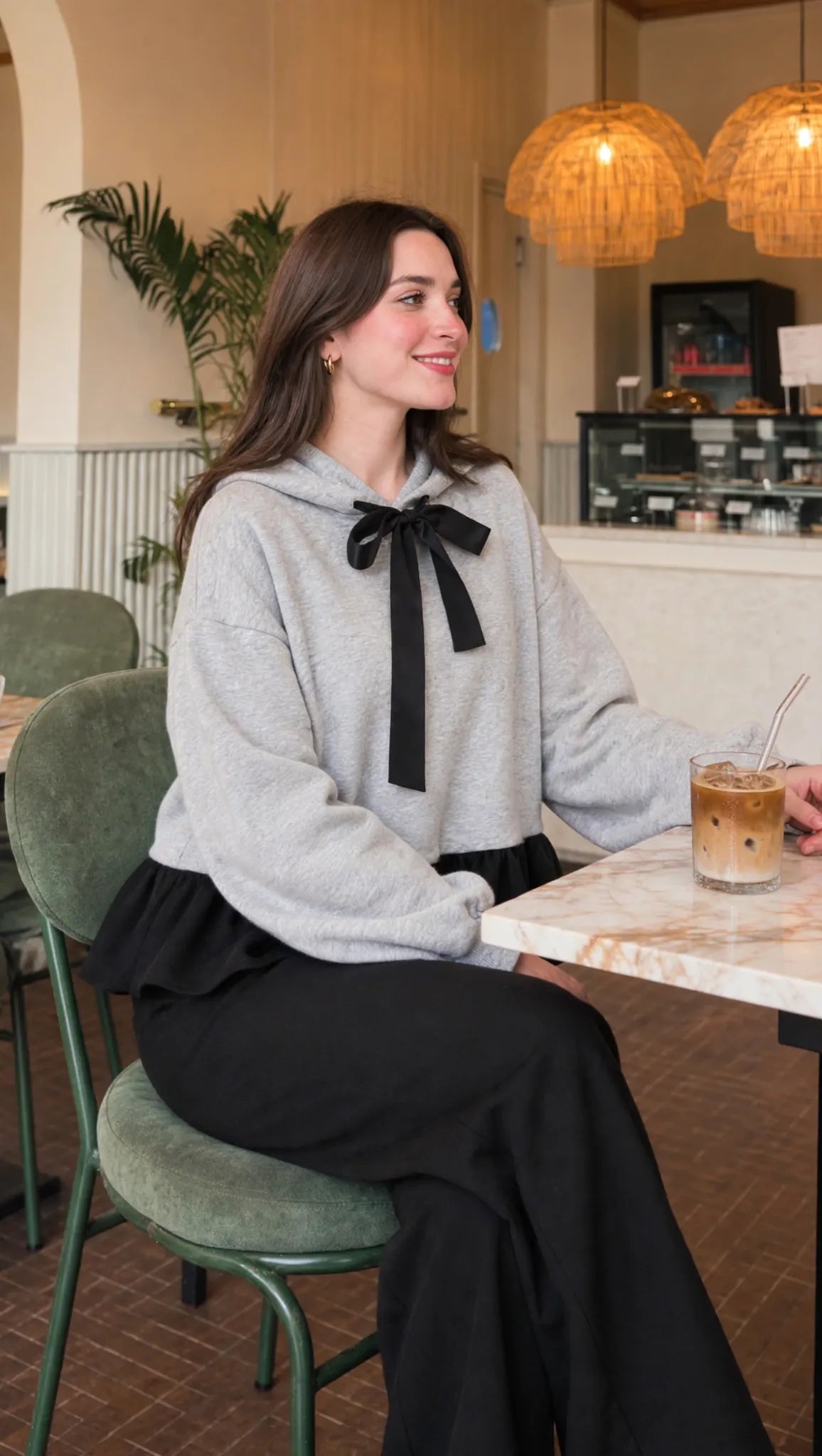 Bow Ruffle Hoodie in grey with black ribbon and ruffle hem, seated view